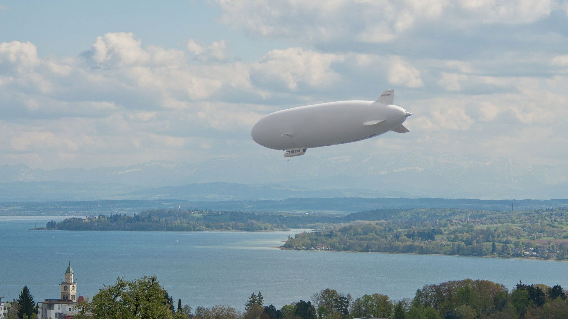 Sicht auf den Bodennsee über dem ein Zeppelin fliegt.