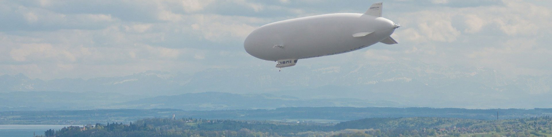 Sicht auf den Bodennsee über dem ein Zeppelin fliegt.